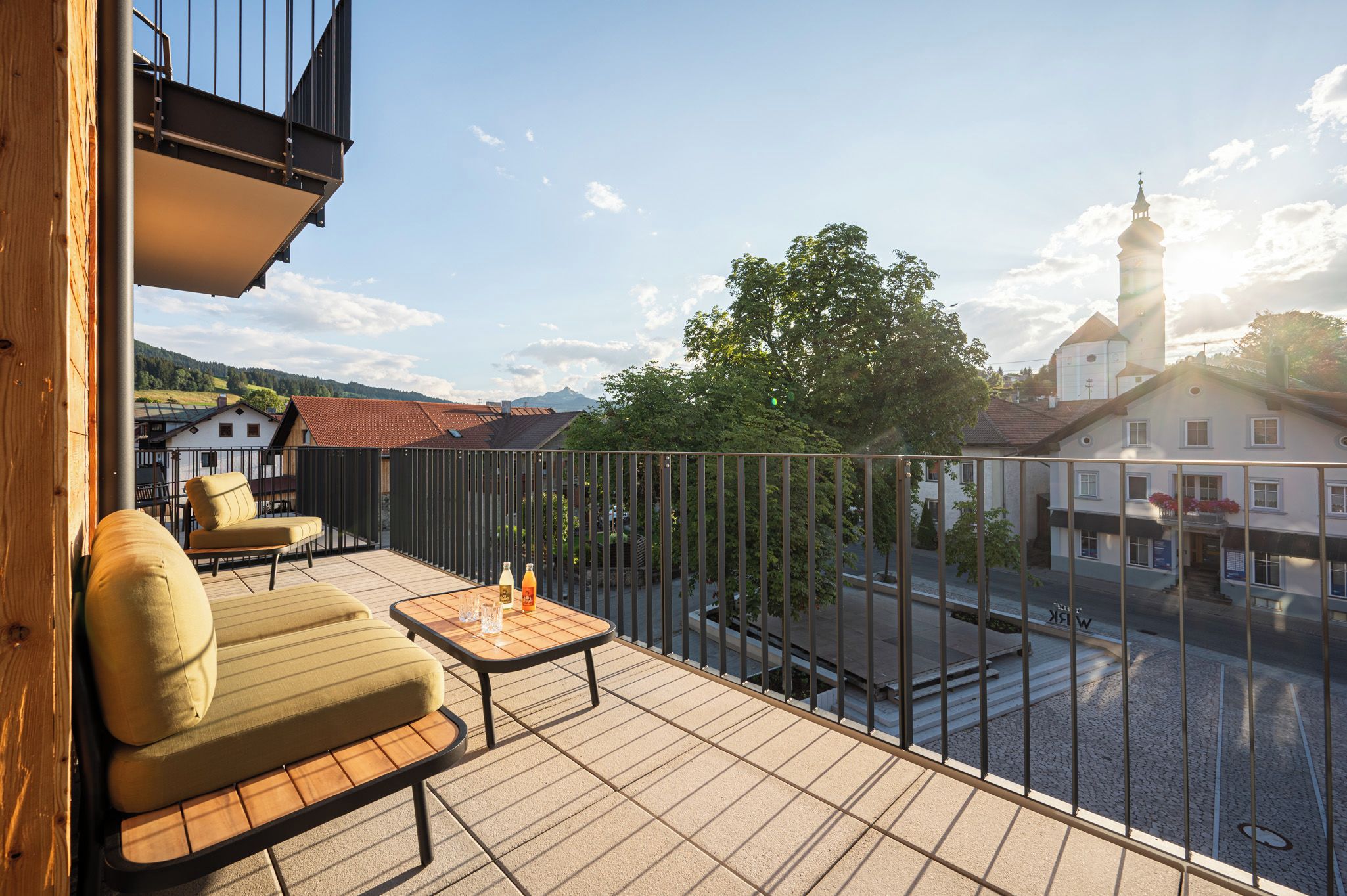 Un balcon avec du mobilier d’extérieur, une vue sur la ville et un bâtiment doté d’une tour.
