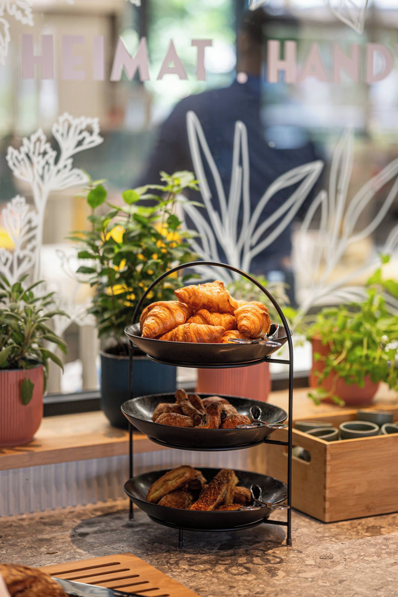 Een dienblad met croissants en een schaal gegrilde kippenvleugels op een aanrecht.