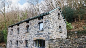 A stone building with multiple windows, a door, and a stone wall. - Millers Loft (Llanrwst)