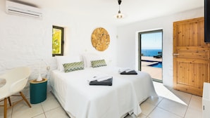 A bedroom with two beds, a view of the sea, an air conditioning unit, and a wooden door. - Villas Maya 3-bedroom villa in fabulous Chorafakia with private pool (Chorafakia)