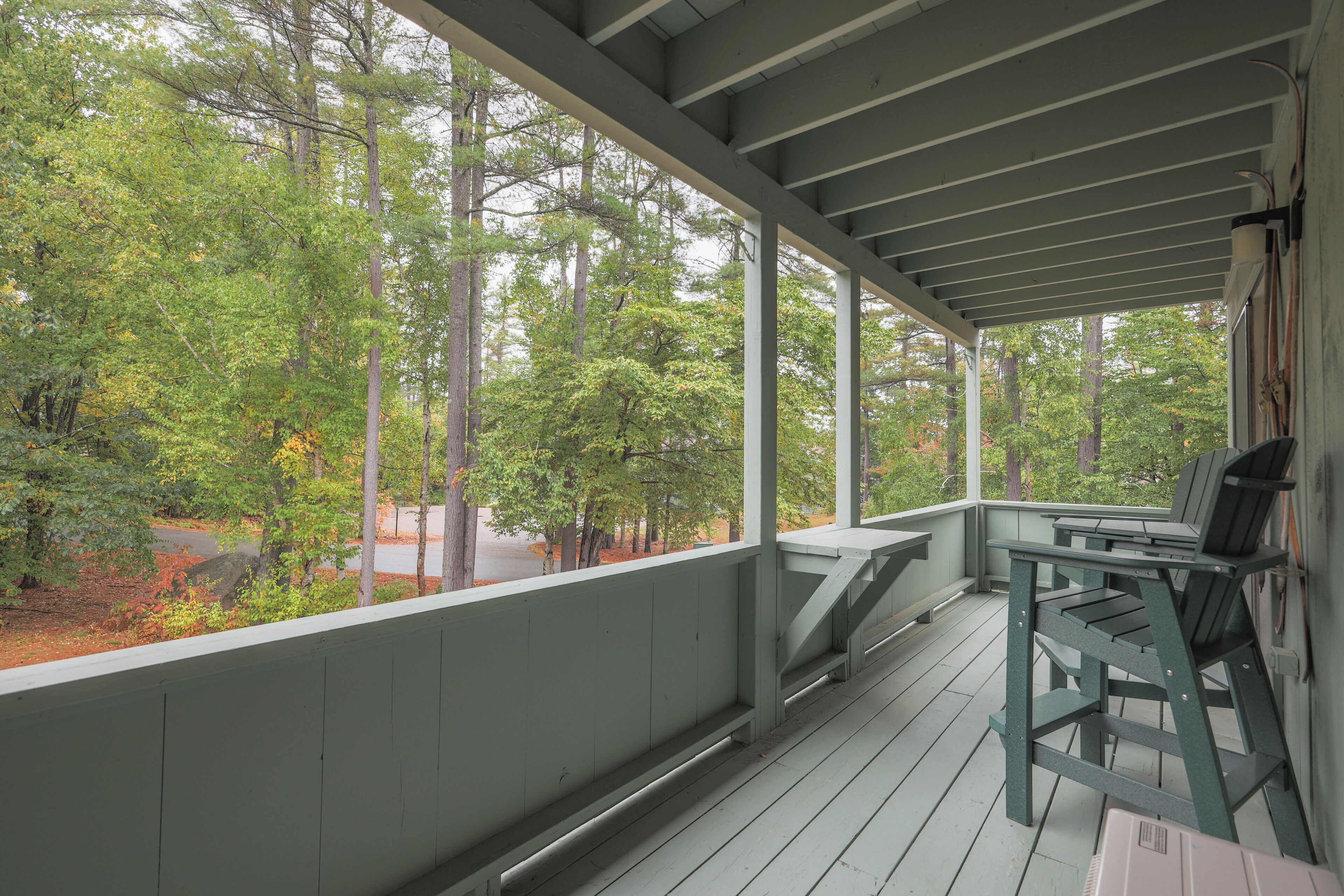 A covered porch with a view of trees and a road.