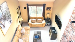 Uma sala de estar com sofá, mesa de centro, televisão e lareira.