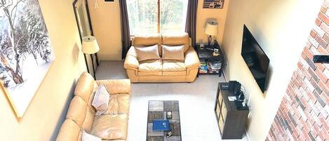 A living room with a sofa, a coffee table, a TV, and a fireplace.