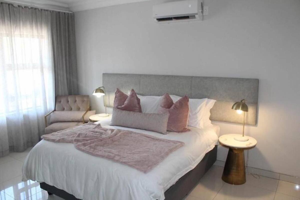 Ein Schlafzimmer mit einem Bett, zwei Nachttischlampen, einem Nachttisch und einer Klimaanlage.