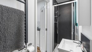 Een moderne badkamer met een douche, wastafel en toilet.