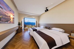 Une chambre d’hôtel avec deux lits, un grand tableau, une vue sur les montagnes et un plancher en bois.