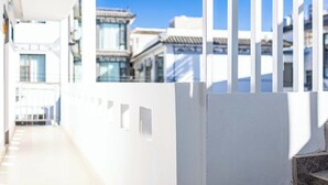 A corridor with a white wall and a metal railing, leading to traditional buildings with tiled roofs. - Dali Haohai Yueju Seascape Guest House (Dali)