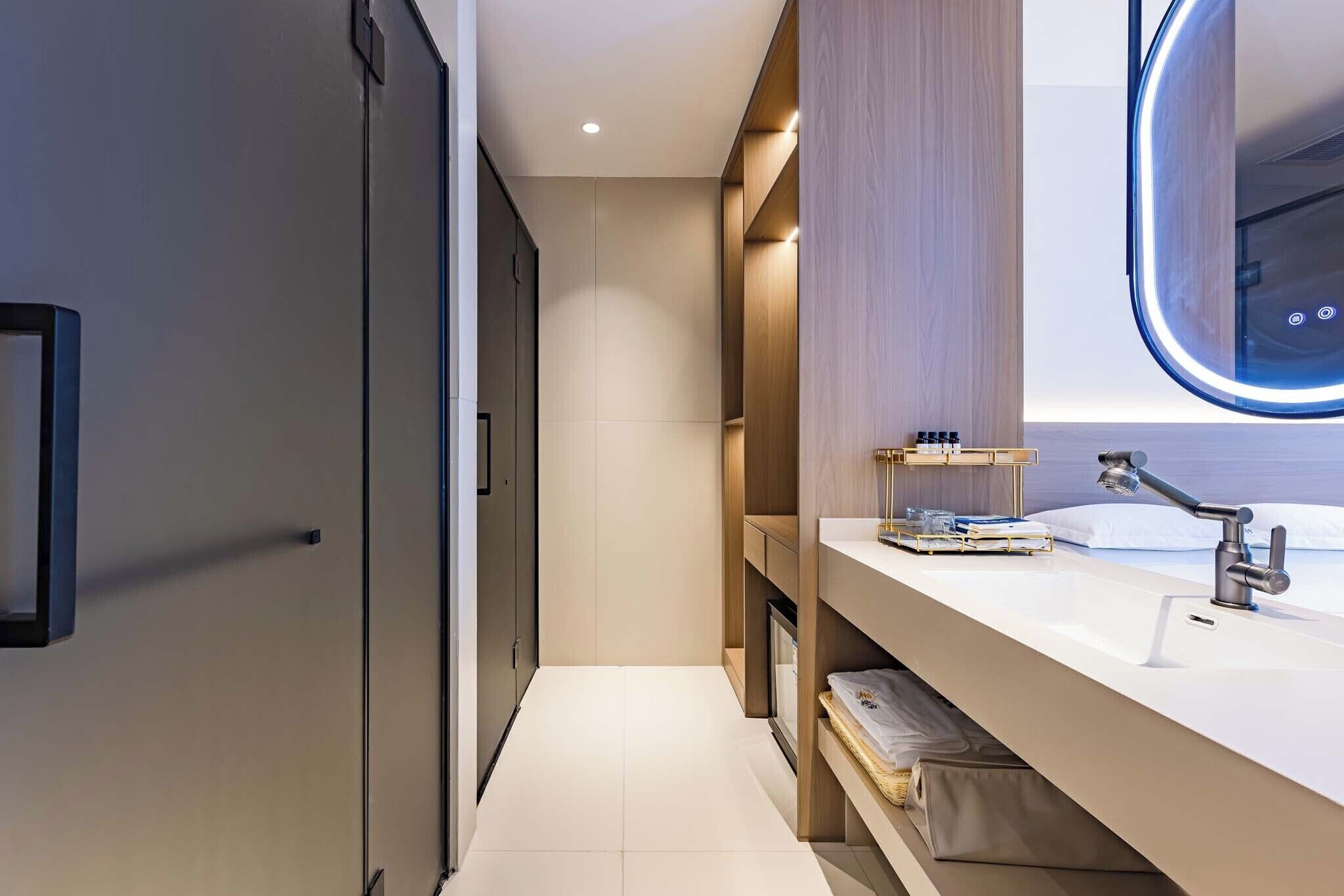 A modern bathroom with a large mirror, a vanity with a sink, and built-in shelving.