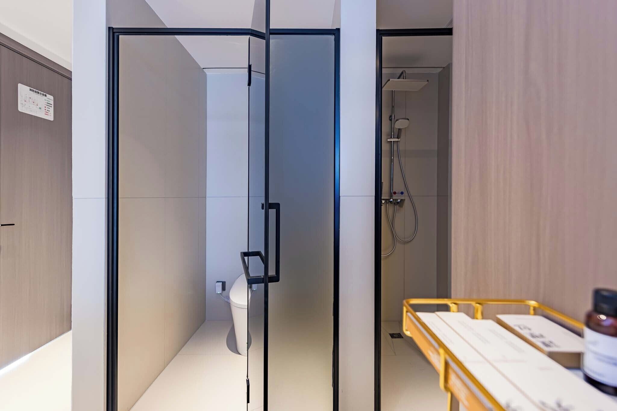 A modern bathroom with a glass partition, a shower area, and a wooden bench with amenities.