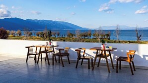 A terrace with wooden tables and chairs, overlooking a body of water and mountains. - Dali Haohai Yueju Seascape Guest House (Dali)