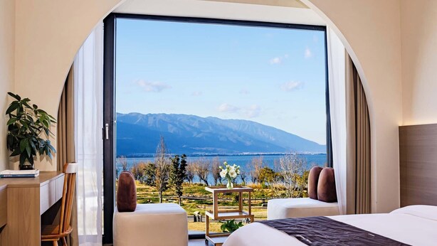 A bedroom with a large window, a desk, two ottomans, and a bed. - Dali Haohai Yueju Seascape Guest House (Dali)