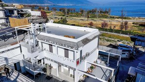A modern building with a flat roof, a covered outdoor seating area, and a view of the sea and mountains in the background. - Dali Haohai Yueju Seascape Guest House (Dali)