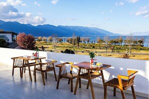Une terrasse avec des meubles en bois, une vue sur un lac et des montagnes en arrière-plan.
