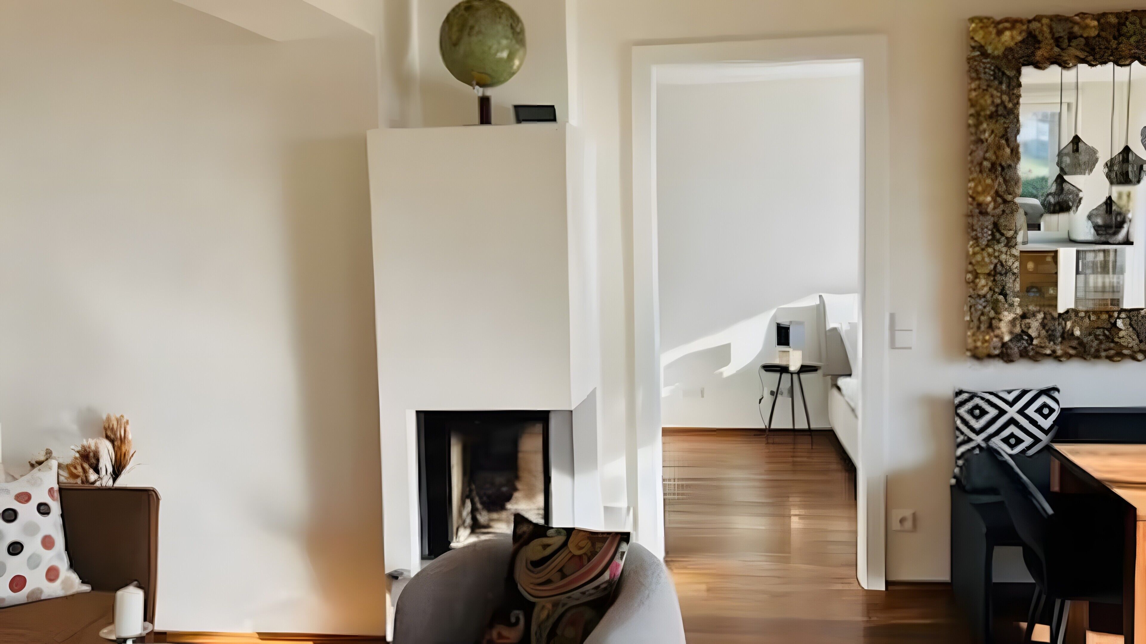 Een moderne woonkamer met een open haard, een eethoek met een zwarte stoel, en een trap naar een hoger gelegen verdieping.