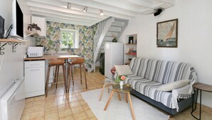 A living room with a sofa, a coffee table, and a TV. - Gîte La P'tite Longère – Independent Cottage in a Peaceful Countryside Setting (Saint-Jacut-les-Pins)