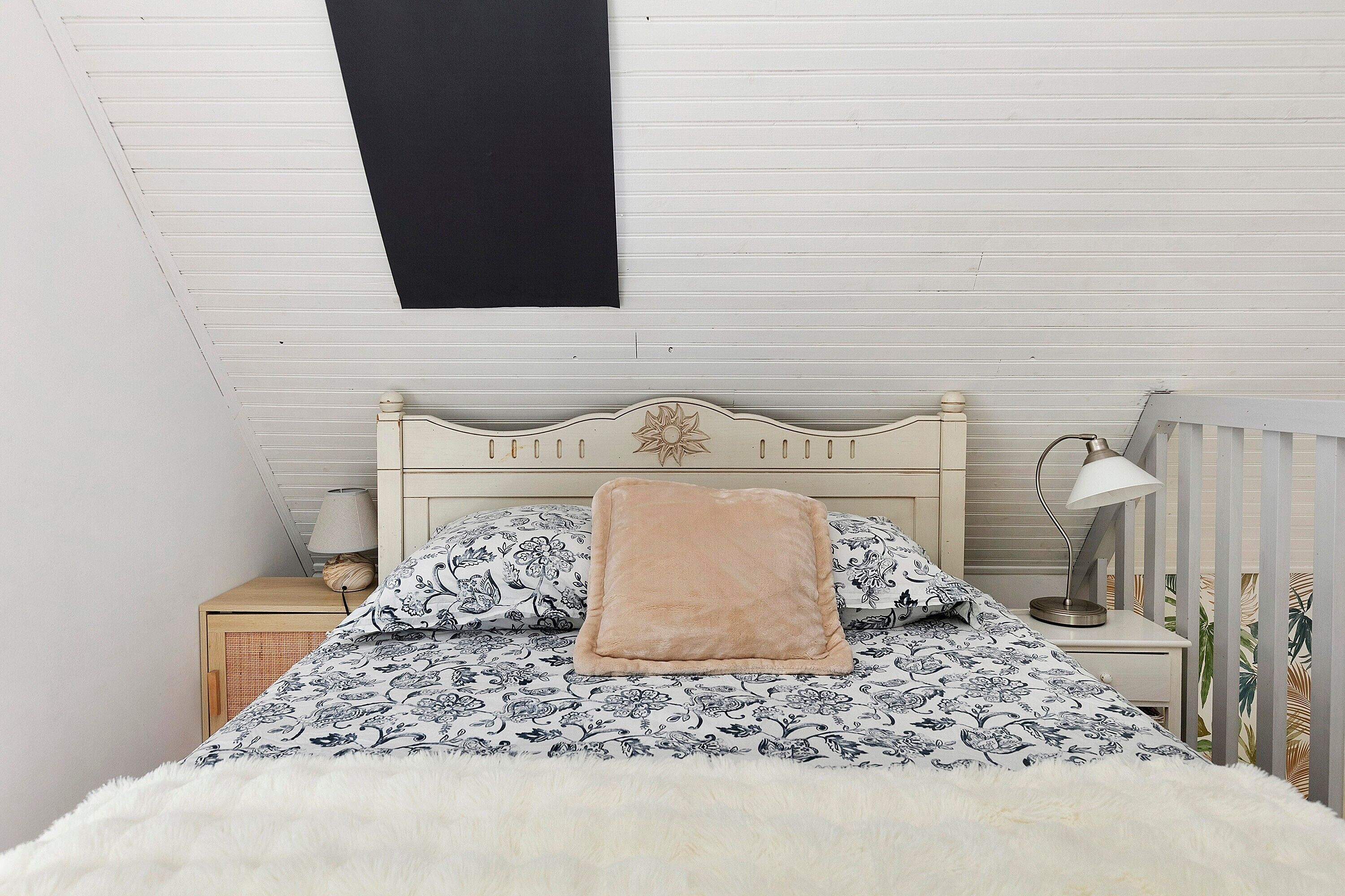 A bedroom with a bed, a nightstand, a lamp, and a ceiling fan.