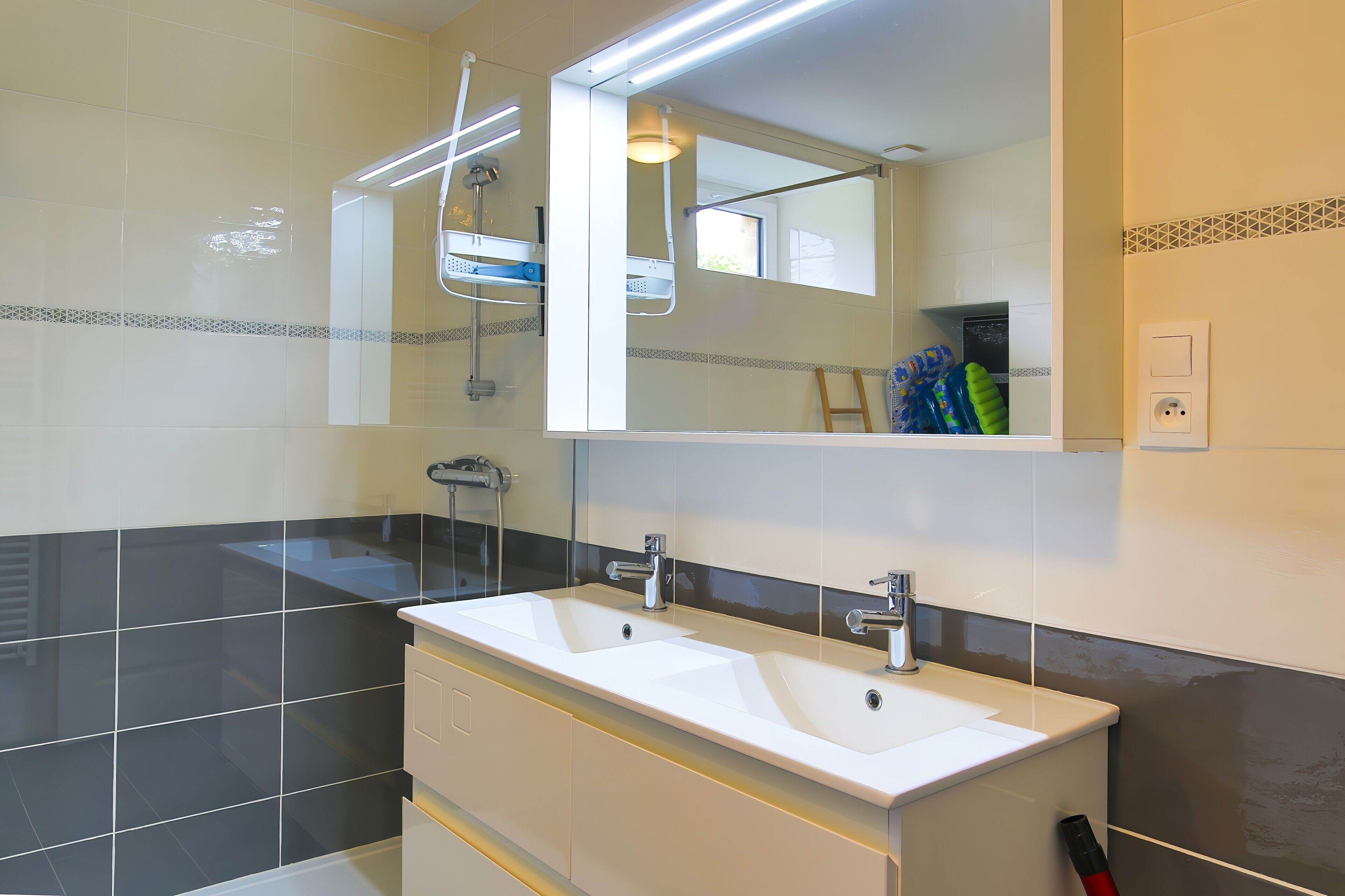 A bathroom with two sinks, a shower, and a large mirror.