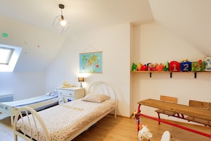Une chambre d’enfant avec deux lits, un bureau, une carte et une étagère remplie de jouets.
