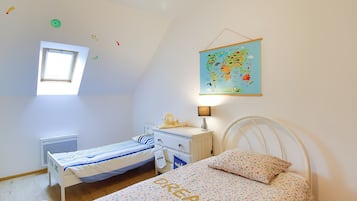 Un dormitorio infantil con literas, un escritorio, un mapa terráqueo y una ventana.