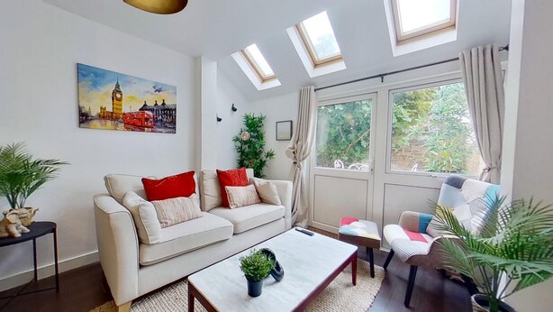 A living room with a sofa, coffee table, and a painting of a cityscape. - Charming 2 Bed Apt with Netflix & Wi-Fi (London)