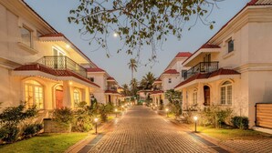A paved pathway leading to a row of buildings with balconies and arched windows. - Staymaster Terra Tango 4BR Villa (Calangute)