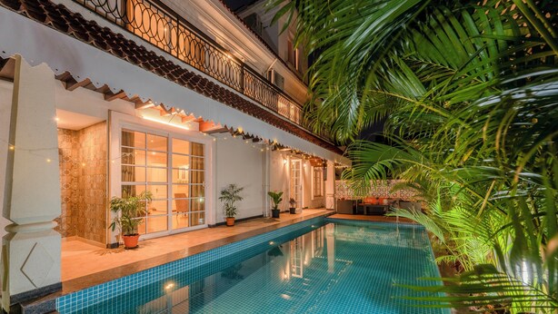 A swimming pool with tiled flooring, potted plants, and a balcony with decorative railings. - Staymaster Terra Tango 4BR Villa (Calangute)