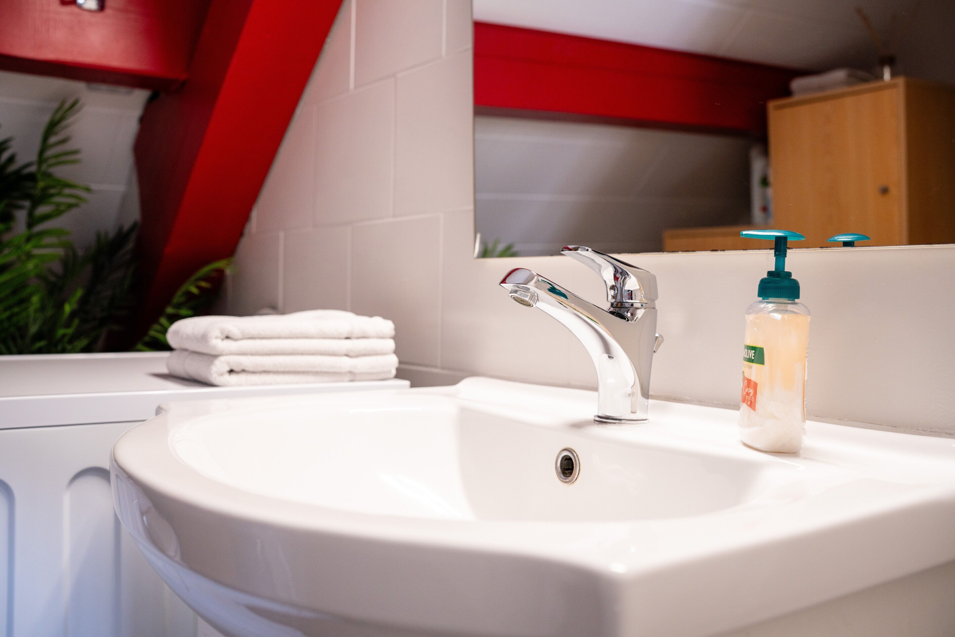 A bathroom with a white sink, a mirror, and a towel rack.