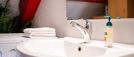 A bathroom with a white sink, a mirror, and a towel rack.
