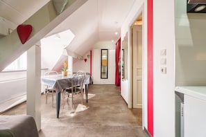 Een eethoek met een tafel en stoelen, een trap en een deur naar een andere kamer.