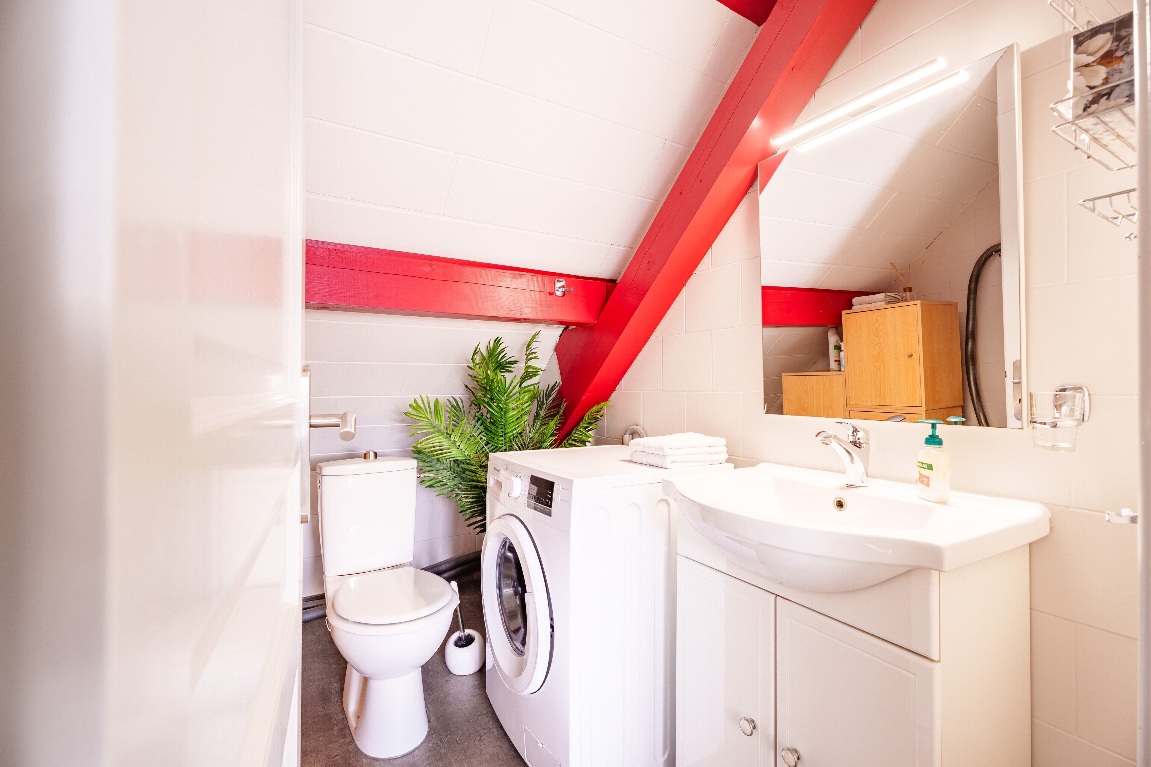 A modern bathroom with a washing machine, toilet, and sink.