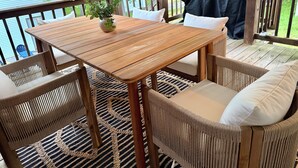 An outdoor deck with a wooden table and wicker chairs, a grill, and a view of greenery. - This is ideal for families, SPIRE & winery visits. (Geneva-on-the-Lake)
