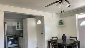 A kitchen with white cabinets, a stove, and a dining area with a table and chairs. - Travellers Villa (Roseau)