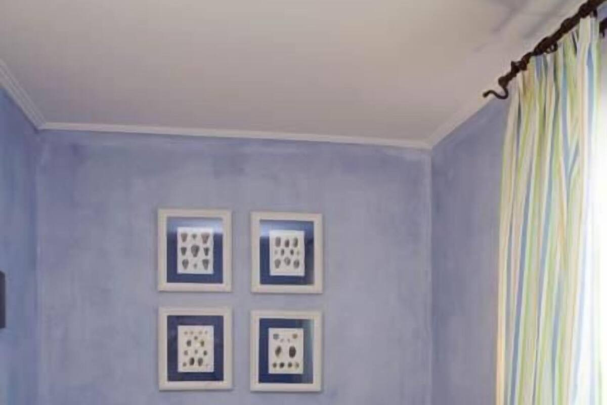 A room with a sofa, a small table, and a wall with framed pictures.