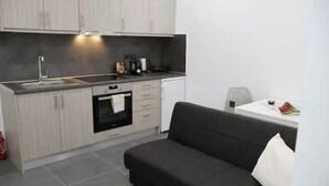 Moderni keittiö, jossa on harmaat kaapit, musta työtaso, sisäänrakennettu uuni ja valkoinen pesuallas.