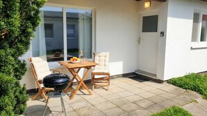 Un patio con una mesa, dos sillas, una parrilla y una puerta.