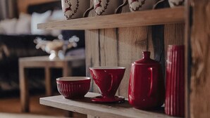 Een houten plank met rode keramieken voorwerpen, waaronder een kom, een beker en een kruik.