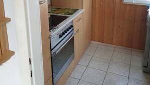 Una cocina pequeña con armarios de madera, una estufa y una ventana.