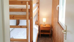 Dormitorio con literas, una mesita de noche pequeña y una lámpara.