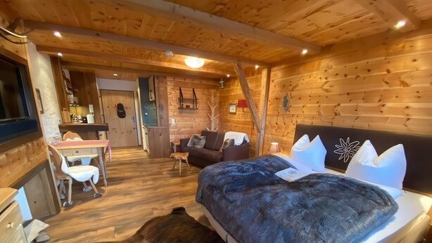 Une chambre confortable dans un chalet en rondins, avec un lit, un bureau, une chaise et un canapé.