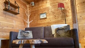 L’intérieur d’un chalet en bois, avec un canapé, une petite table, une lampe et un tableau encadré accroché au mur.