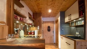Une cuisine moderne avec des meubles en bois, une cuisinière encastrée et un mur recouvert d’un tableau noir.
