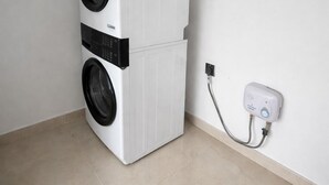 Máquina de lavar e secar compacta, branca e fixada na parede, com tomada e cabo.