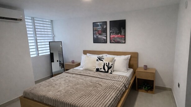 Quarto com uma cama, duas mesas de cabeceira, um espelho e duas quadros na parede.