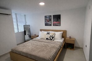 A bedroom with a bed, two bedside tables, a mirror, and two wall-mounted pictures. - Charming Luquillo Retreat Minutes to Beach & Kiosks (Luquillo)