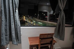 Une chambre avec vue sur un pont et une rue animée, de nuit.