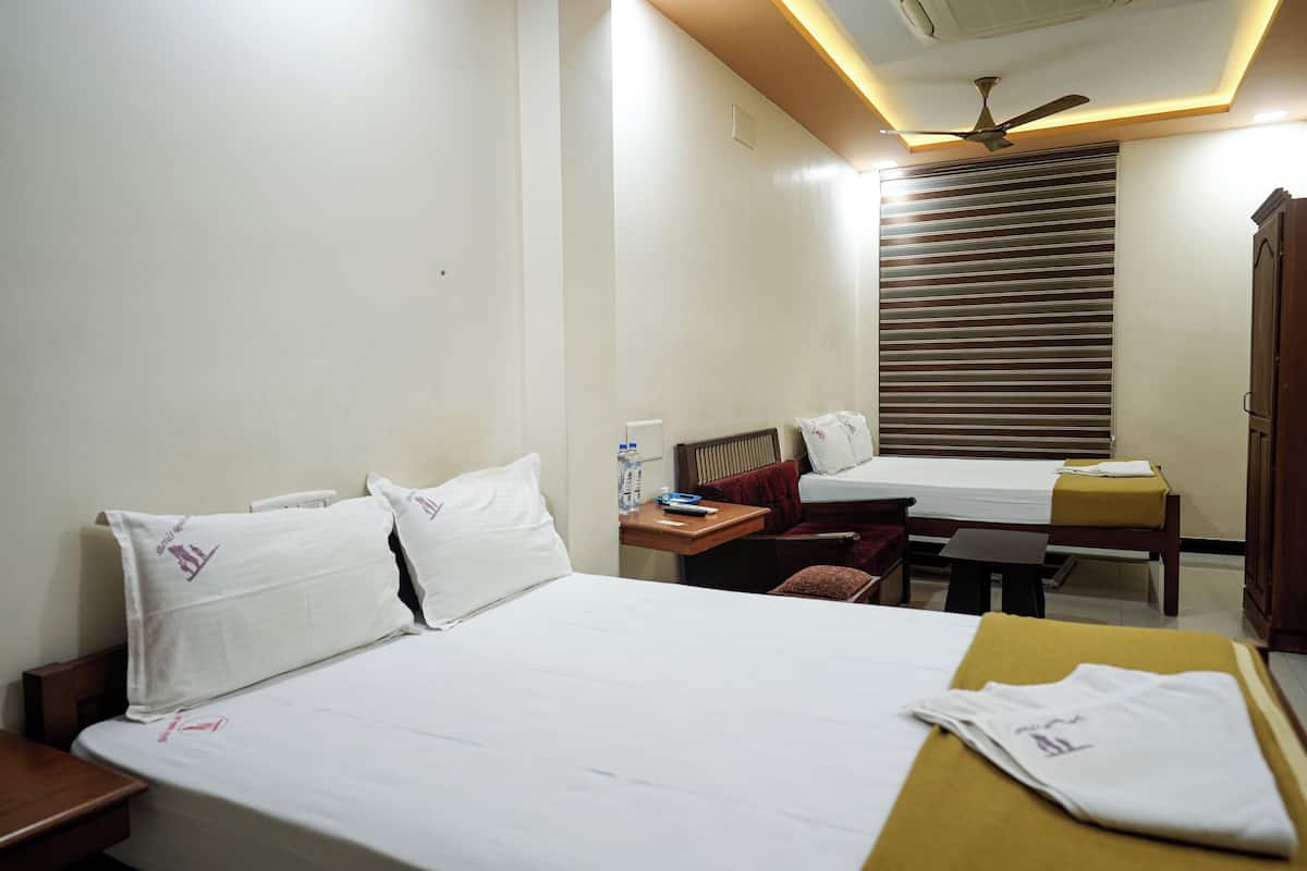 A hotel room with a bed, bedside table, desk, chair, and wardrobe.