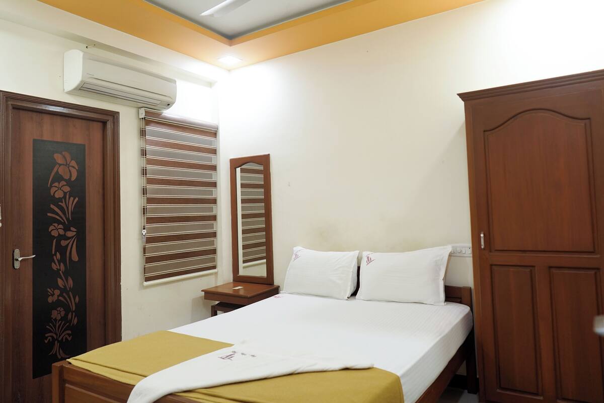 A bedroom with a bed, a wardrobe, a mirror, and an air conditioning unit.