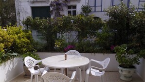 A round table with four white chairs, surrounded by potted plants and a white wall. - R de C apartment with private terrace and parking 100 M from the sea (La Baule-Escoublac)