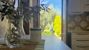 Een keuken met uitzicht op een tuin, een vaas met planten en een betegelde achterwand.