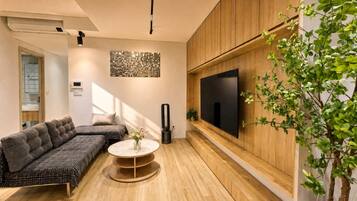 Un salon moderne avec un canapé, une table basse, un téléviseur fixé au mur et une plante en pot.